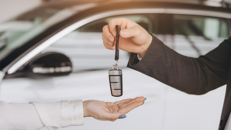 Un homme remettant une clé intelligente de voiture à une femme