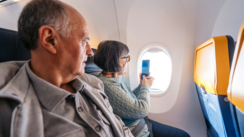 Un couple de personnes âgées regardant par la fenêtre dans un avion