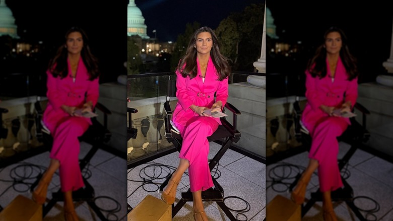 Kaitlan Collins assise sur une chaise dehors tout en portant un tailleur-pantalon rose vif