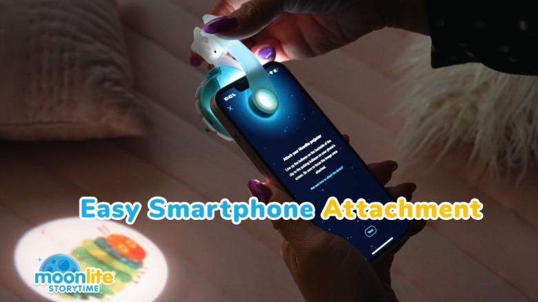 Une femme attache le projecteur Moonlight Storytime à son iPhone
