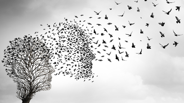 Concept de mort d'un arbre avec des branches en forme de profil facial et des oiseaux partant en groupe qui se fondent en quelques-uns