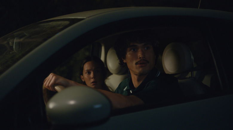 Charles Melton dans le rôle d'Austin Davis et Cailee Spaeny dans le rôle d'Ashley Miller assis dans leur voiture avec des expressions choquées dans Beef