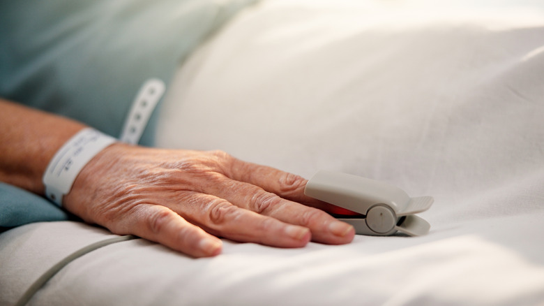 Gros plan sur la main d'un patient avec un oxymètre fixé au doigt.
