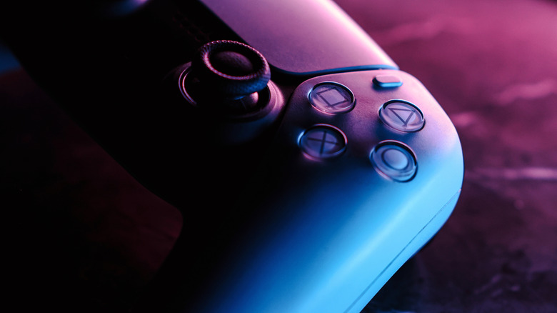 Une manette PS5 sous un éclairage d’ambiance bleu et violet.
