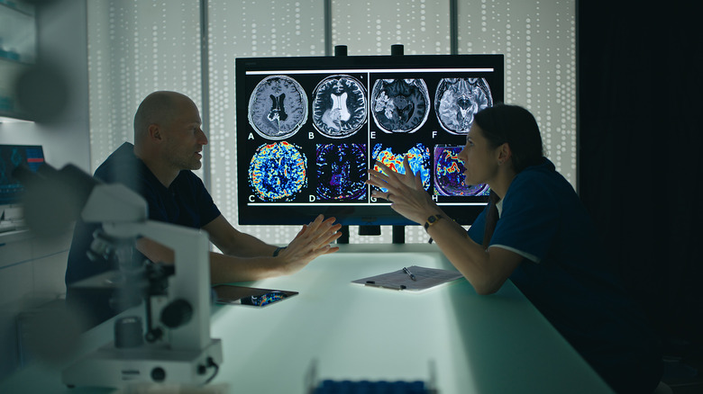 Deux professionnels de santé discutent devant un écran affichant des images d’une IRM.
