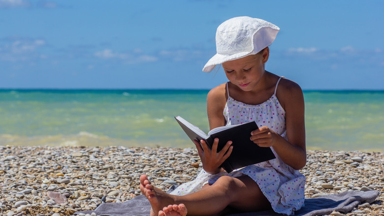 enfant lisant sur la plage
