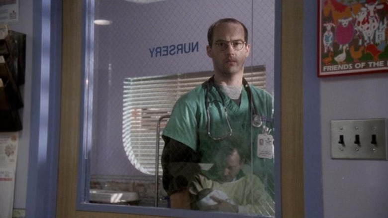 Mark regarde Sean tenant son bébé à travers la fenêtre de la crèche du Pitt