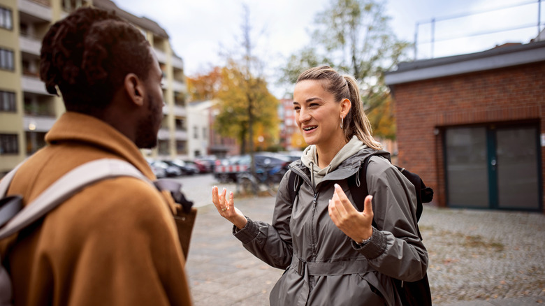 une jeune femme utilise des gestes de la main tout en communiquant avec un homme dans une langue étrangère