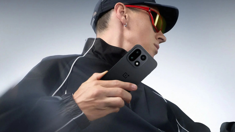 Une personne vêtue de noir pose avec le OnePlus 15.