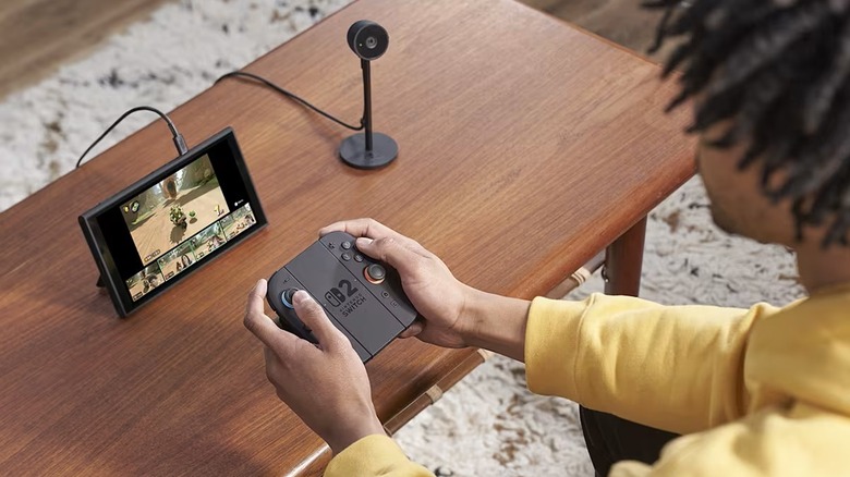 Quelqu'un jouant à la Nintendo Switch 2 en mode portable avec le Joy-Con 2 et un appareil photo.