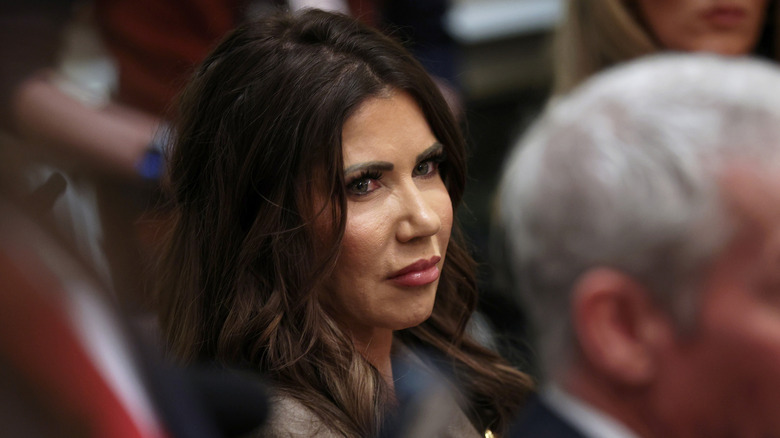 Kristi Noem regarde sur le côté et fronce légèrement les sourcils