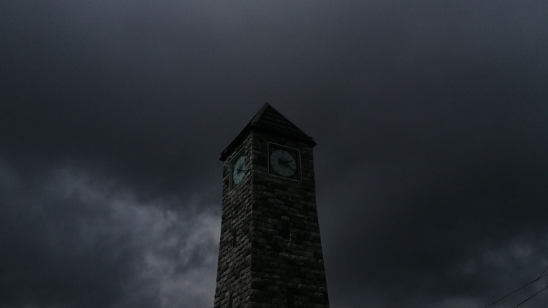 Une tour de l’horloge avec de sombres nuages ​​d’orage derrière elle.