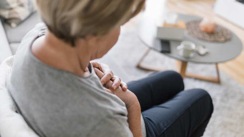 Femme assise avec les mains sur la poitrine souffrant de douleur