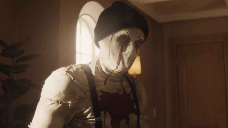 Hunter Doohan dans le rôle de Muse portant un masque effrayant et une casquette de ski dans un bureau de Daredevil : Born Again Saison 1