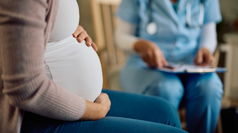 Vue en coupe médiane d'une femme enceinte assise avec un médecin