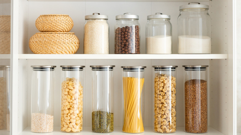 Armoire de cuisine contenant des bocaux en verre contenant du riz, des pâtes et d'autres produits secs.