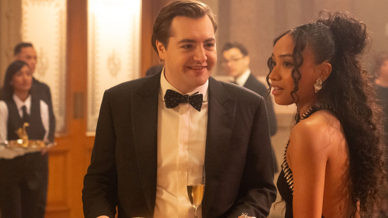 Michael Gandolfini dans le rôle de Daniel Blake portant un smoking lors d'un cocktail à côté de Genneya Walton dans le rôle de BB Urich dans Daredevil : Born Again