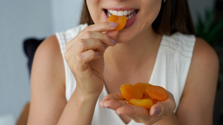 Femme mangeant une poignée d’abricots secs