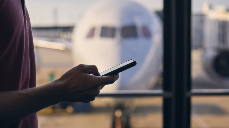Un voyageur utilise son téléphone à l'aéroport