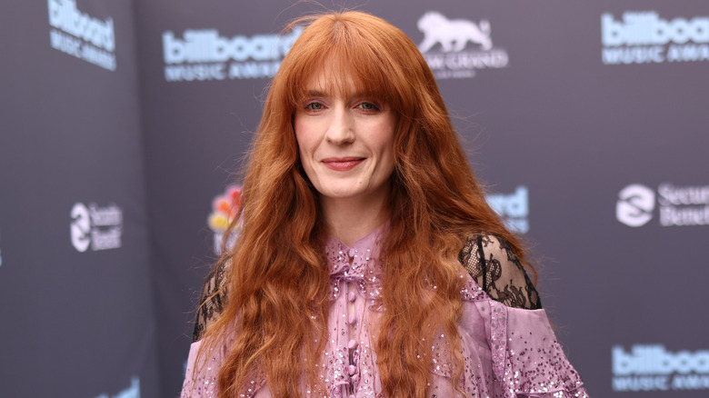 Florence Welch sourit lors d'un événement sur le tapis rouge tout en portant une robe rose clair avec des manches en dentelle