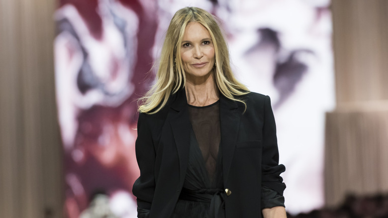 Elle MacPherson défile dans une robe noire transparente associée à un blazer surdimensionné