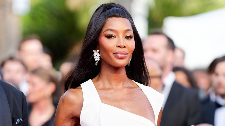 Naomi Campbell porte une robe blanche et un maquillage glamour lors d'un événement en plein air