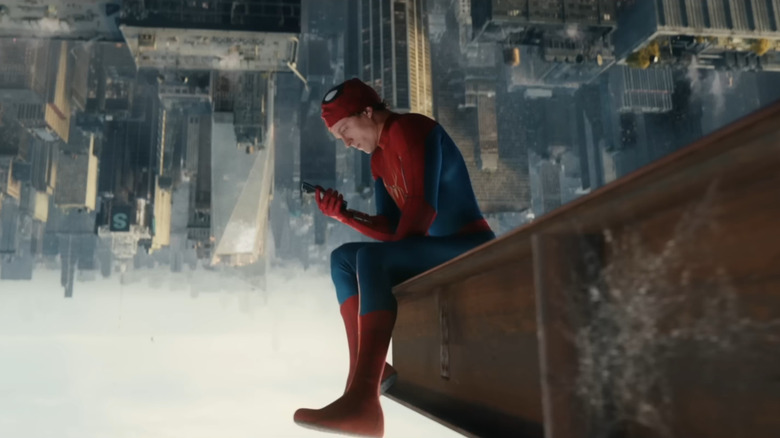 Tom Holland dans le rôle de Peter Parker, assis à l'envers sur une poutre en acier surplombant New York et regardant son téléphone dans Spider-Man : Brand New Day