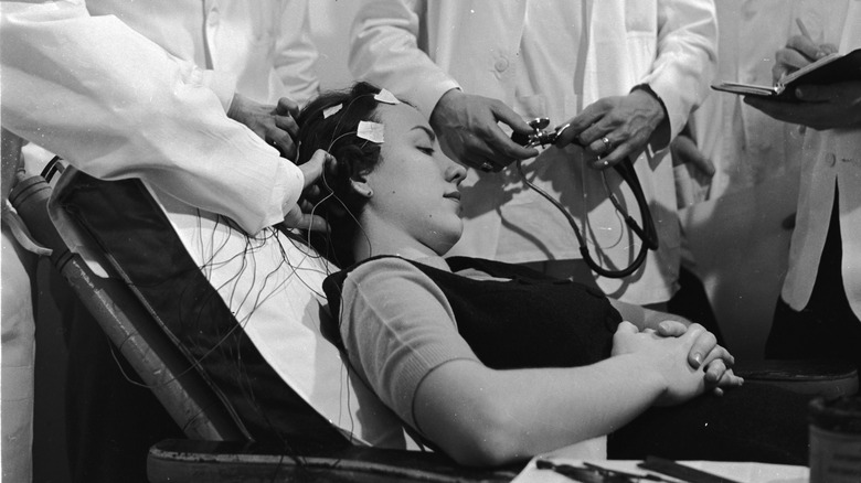 Les scientifiques placent des électrodes sur la tête d'une femme.