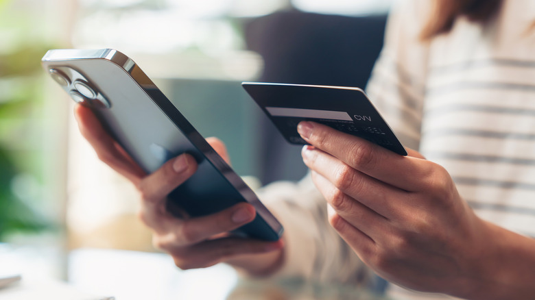 une femme sans visage tient un iphone et une carte de crédit