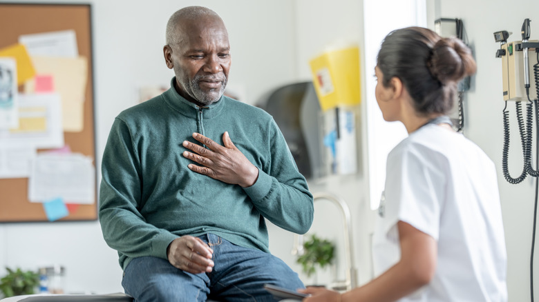 Homme avec la main sur la poitrine parlant avec un professionnel de la santé