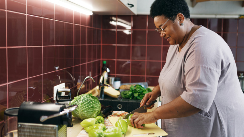Femme coupant des légumes sur un comptoir de cuisine