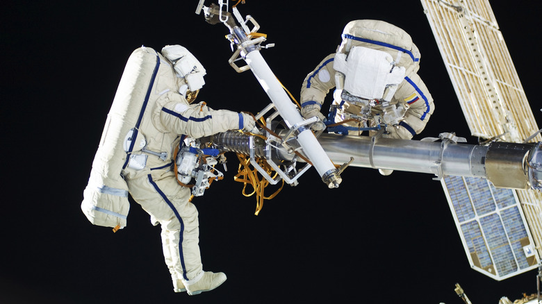 Deux astronautes sur l'ISS lors d'une sortie dans l'espace, réparant le bras