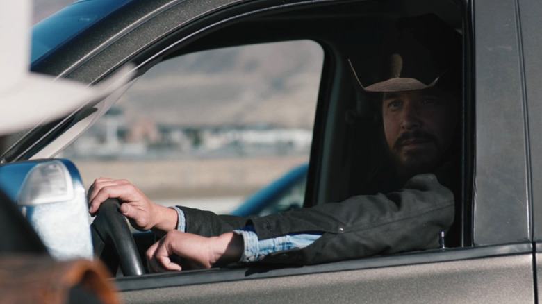 Rip Wheeler est assis dans sa voiture et regarde par la fenêtre alors qu'il parle à quelqu'un hors écran à Yellowstone