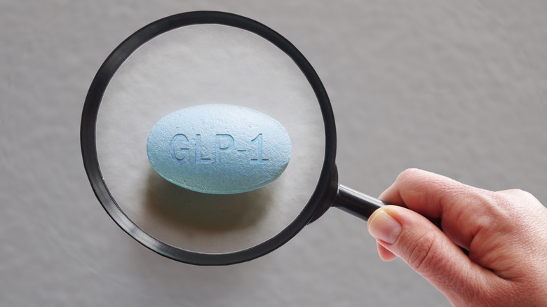 Une main tenant une loupe sur une pilule GLP-1