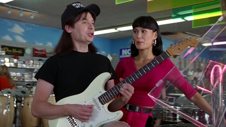 Mike Myers dans le rôle de Wayne Campbell brandit un Fender tandis que Tia Carrere dans le rôle de Cassandra Wong regarde dans Wayne's World