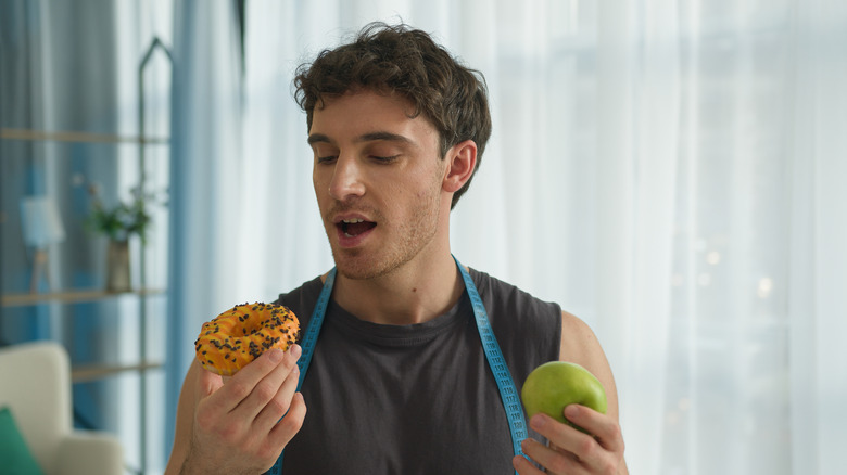 Homme tenant un beignet et une pomme