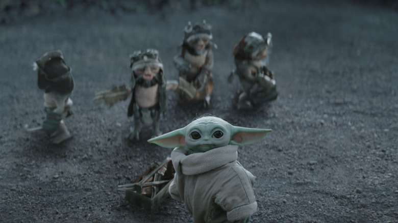 Les Anzellans en arrière-plan avec Grogu debout près d'une boîte à outils dans The Mandalorian et Grogu