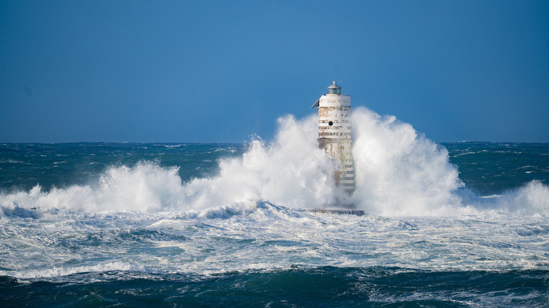 Une très grosse vague entrant en collision avec un phare.