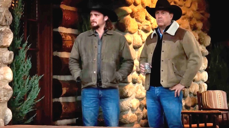 Kayce Dutton de Luke Grimes se tient à côté de John Dutton de Kevin Costner sur le porche d'un ranch à Yellowstone