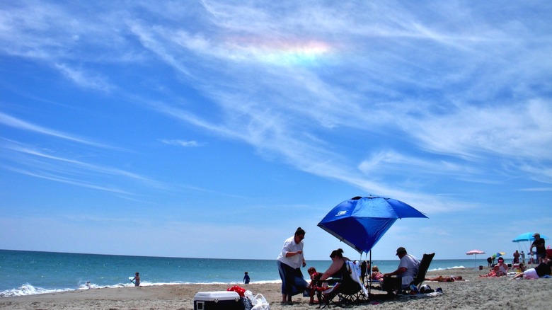 Des gens sur une plage avec un arc-en-ciel de feu de couleur arc-en-ciel dans le ciel