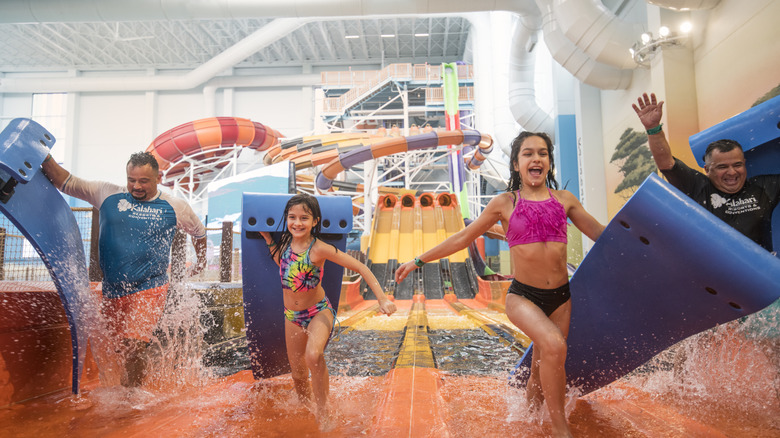 Enfants et adultes jouant sur le toboggan aquatique du parc couvert du Kalahari.