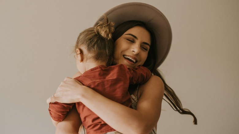 Une femme tient son enfant dans ses bras.