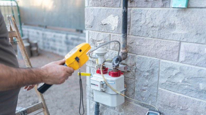 Technicien en gaz visitant un moniteur de gaz extérieur sur la maison