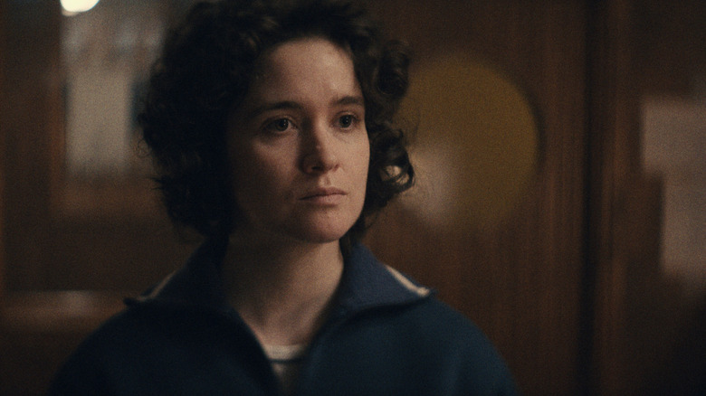 Alice Englert dans le rôle d'Anastasia Belikova portant son uniforme d'astronaute alors qu'elle se tient debout dans un bureau de la Cité des étoiles
