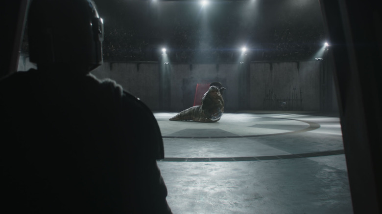 Pedro Pascal dans le rôle de Din Djarin debout près d'une porte d'une arène regardant Jeremy Allen White dans le rôle de Rotta le Hutt devant un grand public dans Star Wars : Le Mandalorien et Grogu