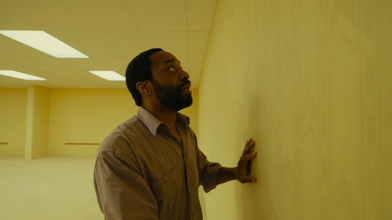Chiwetel Ejiofor dans le rôle de Clark touchant un mur jaune dans Backrooms
