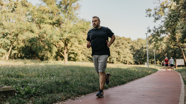 Homme d'âge moyen en surpoids faisant du jogging dans un parc