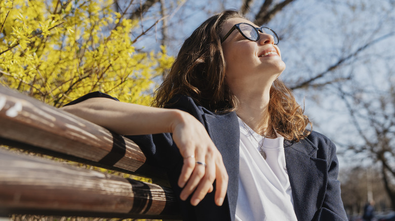 Femme assise sur un banc à l'extérieur et souriante