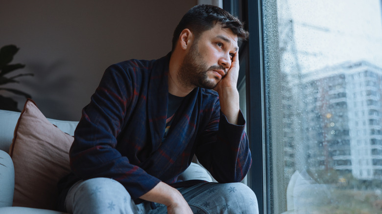 Homme avec la tête dans la main en regardant par la fenêtre