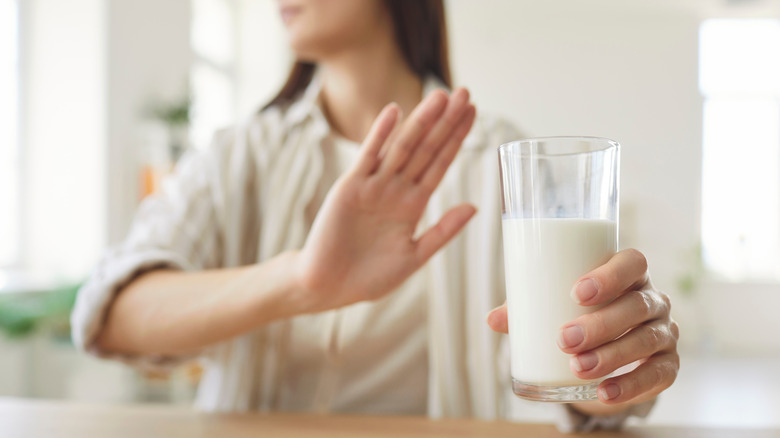 Femme levant la main pour refuser un verre de lait